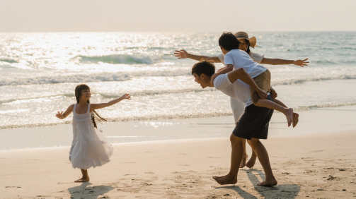 Asian young happy family enjoy vacation on beach in the evening. Dad, mom and kid relax playing together near sea when sunset while travel holiday. Lifestyle travel holiday vacation summer concept.