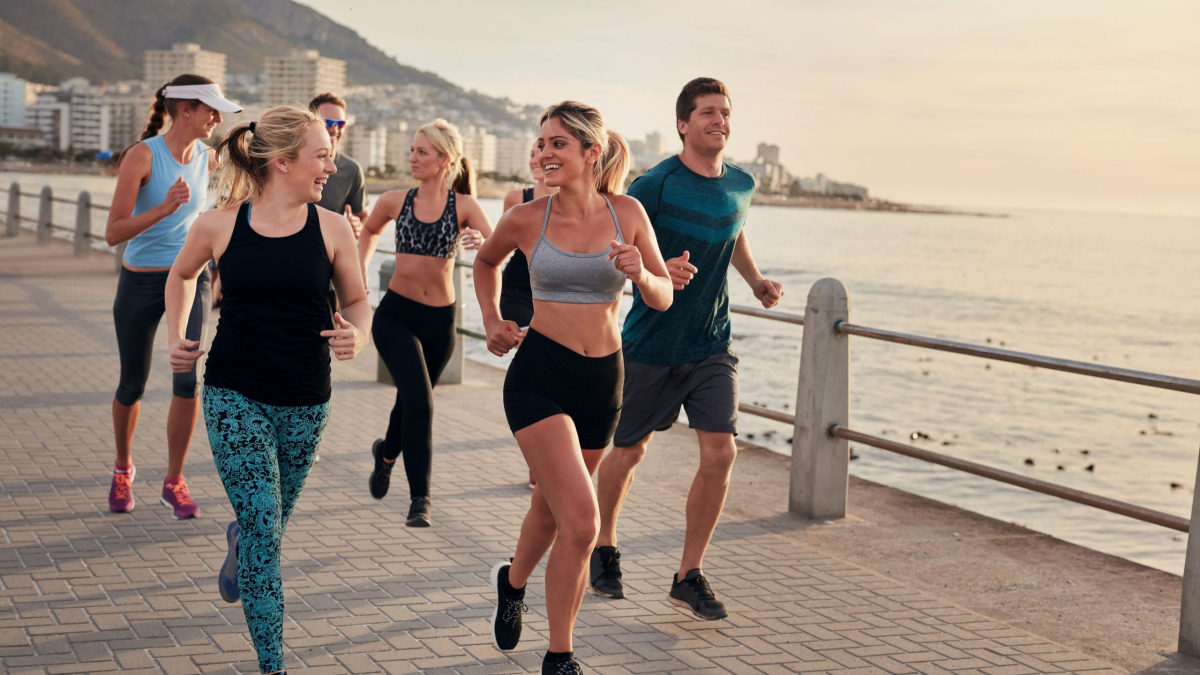 50988703 - portrait of young runners enjoying workout on the sea front path along the shoreline.  running club group running along a seaside promenade.