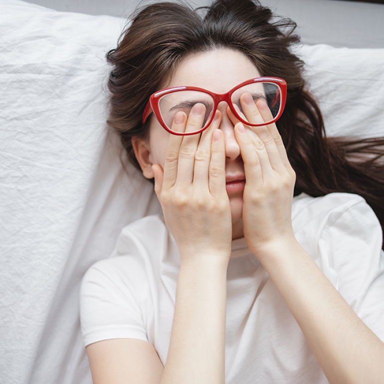 Young woman rubs her eyes after using glasses. Eye pain or fatigue concept, poor vision.